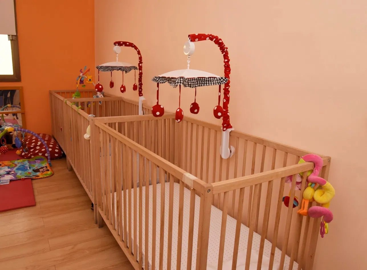 Row of wooden cots in the infant sleep room
