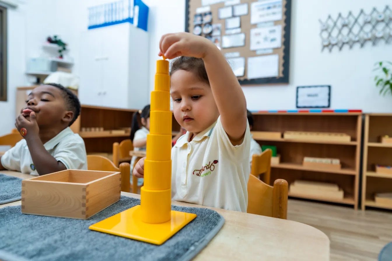 Toddler stacking the pink tower Montessori material