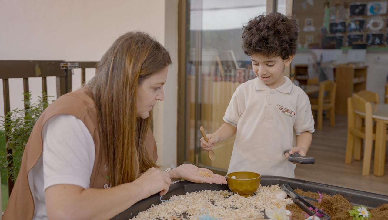 Teacher and child exploring a nature sensory tray together