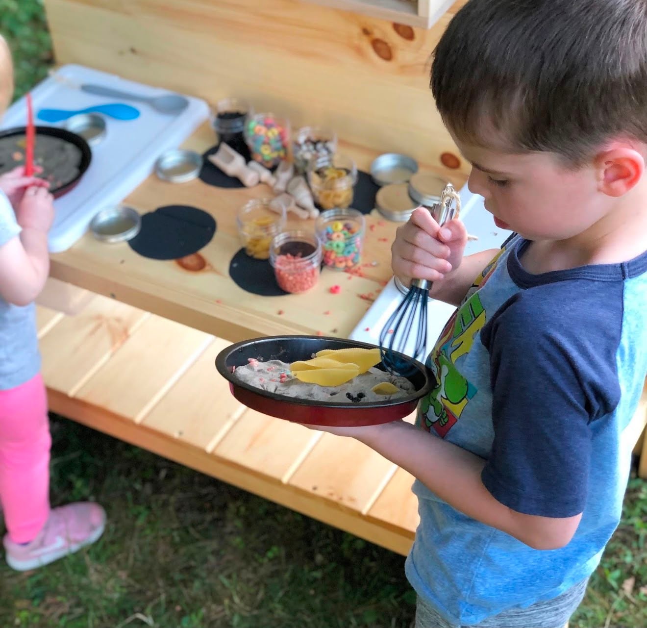 Children exploring a mud pie and pasta sensory kitchen activity