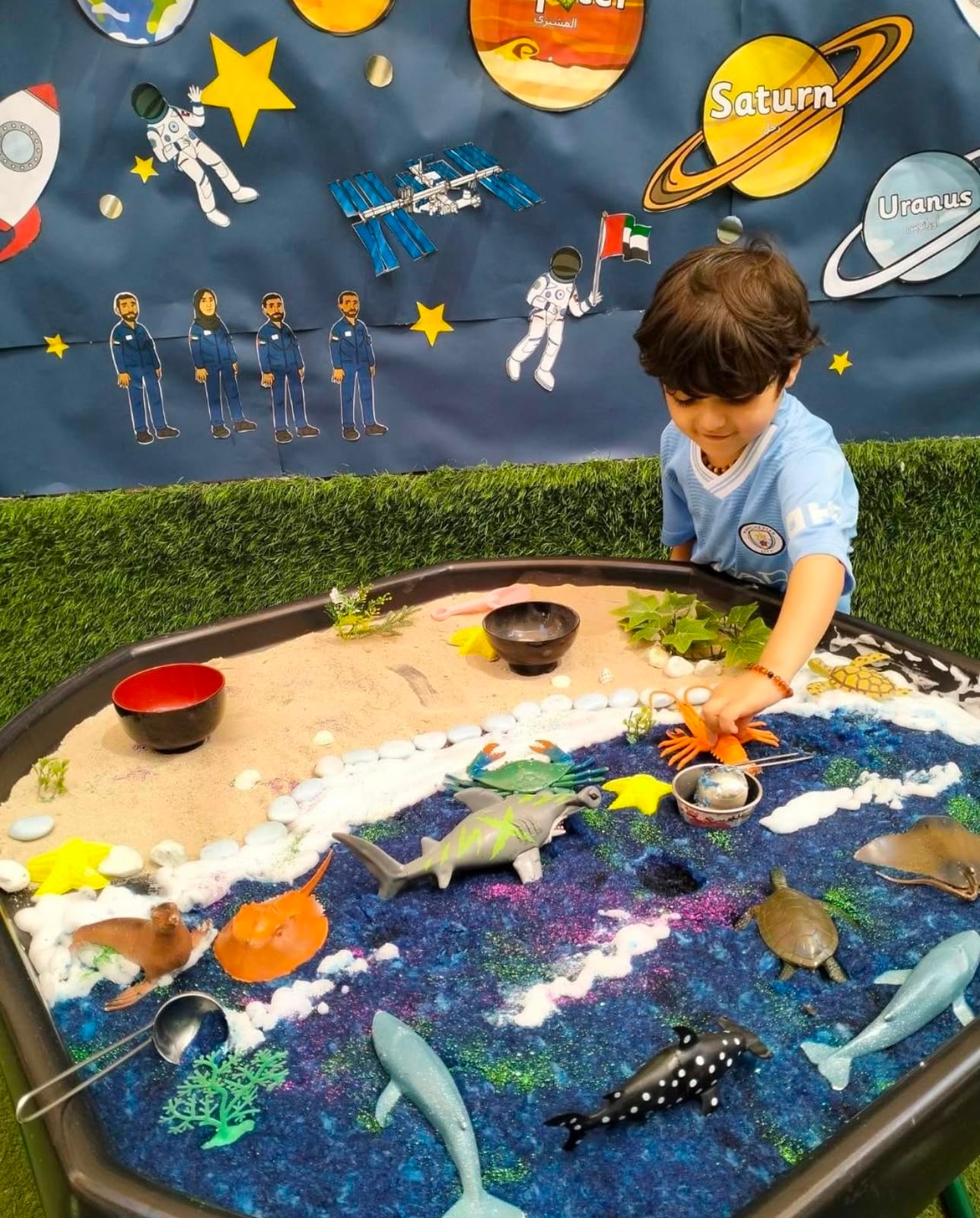 Child exploring a space and ocean themed sensory tray