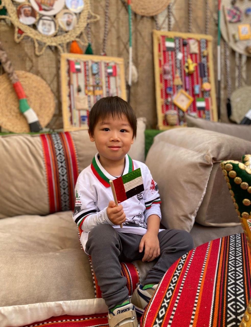 Child holding the UAE flag during a National Day celebration at Ladybird Nursery