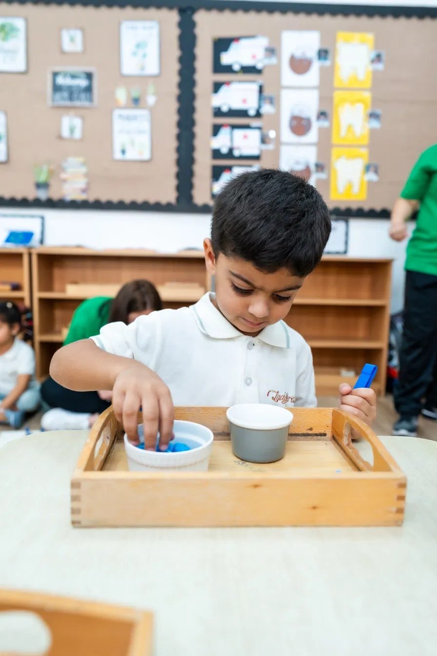 Boy practising pouring with a practical life tray