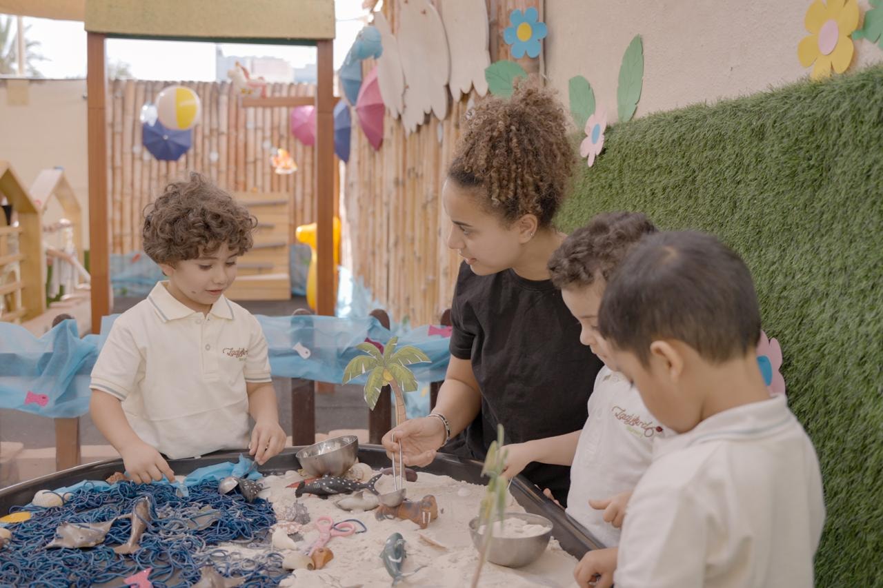 Teacher and children exploring a beach-themed sensory water table