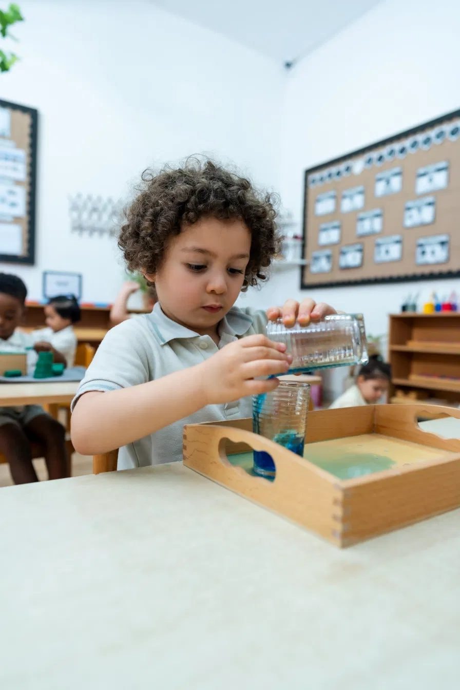 Boy pouring coloured water between glasses