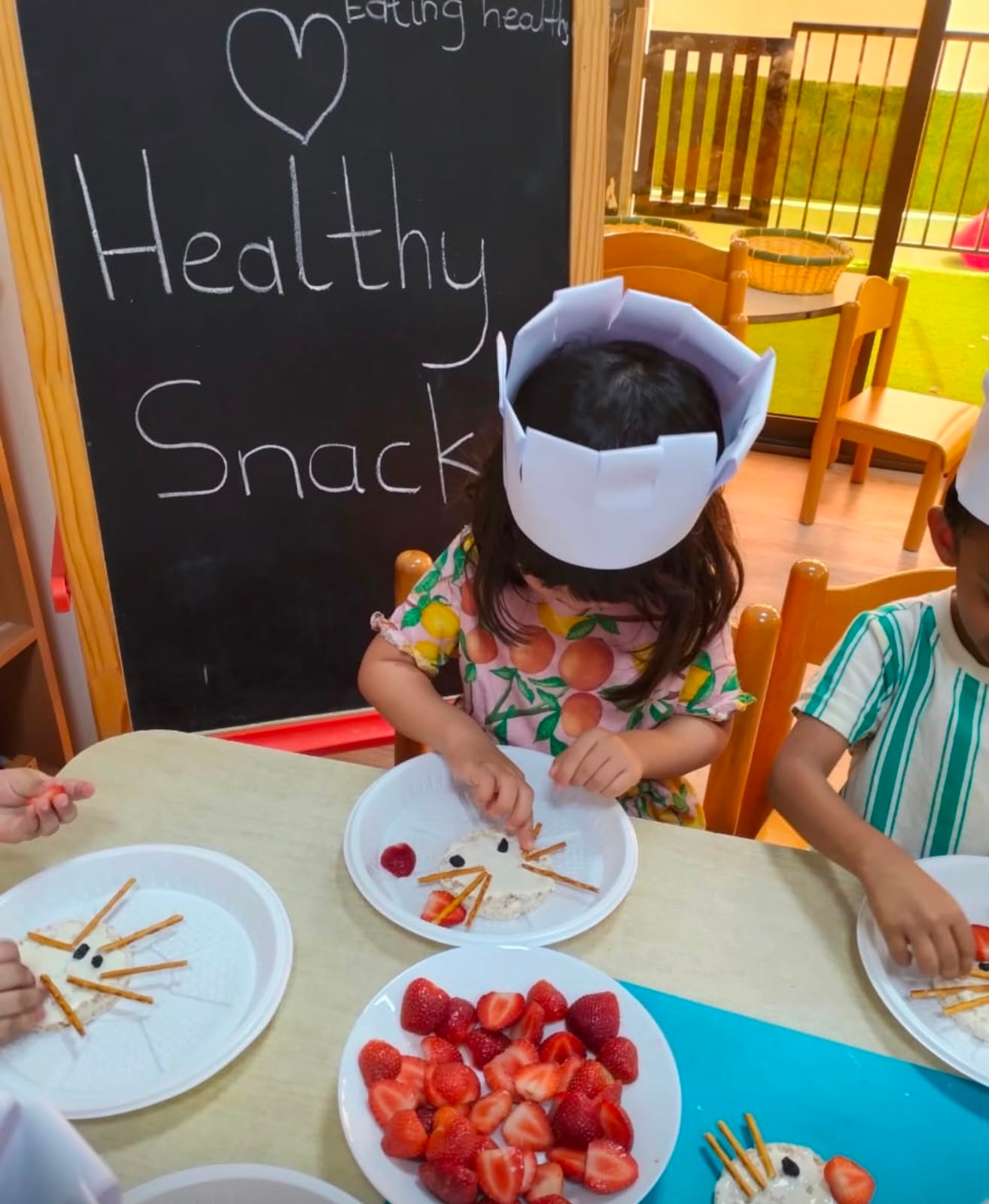 Children in chef hats preparing a healthy snack