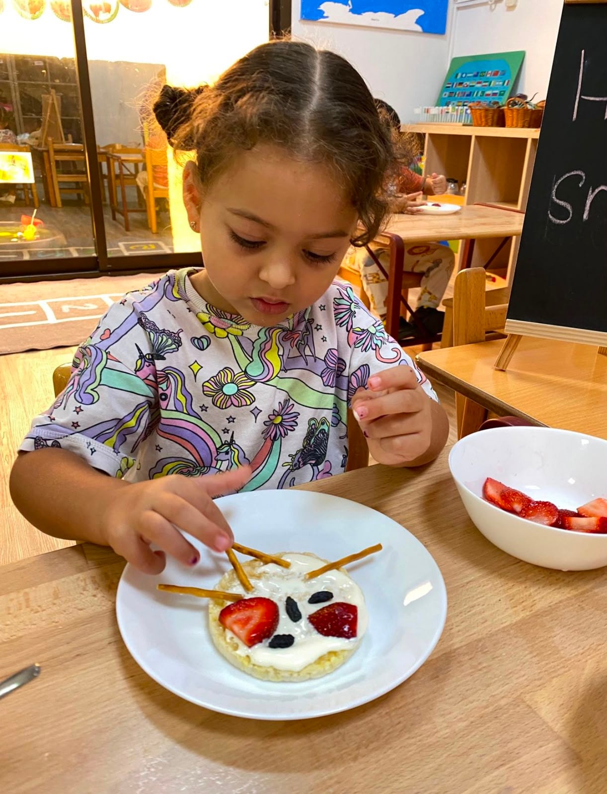 Child decorating a healthy snack plate with strawberries