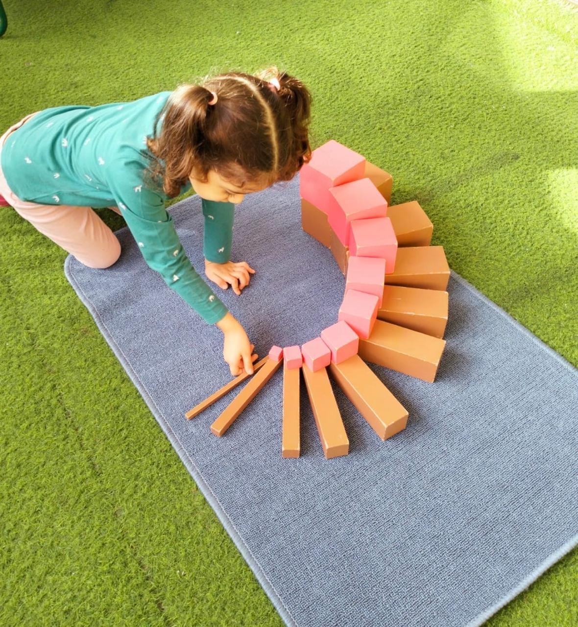 Child arranging Montessori pink tower and brown stair sensorial materials at Ladybird Nursery